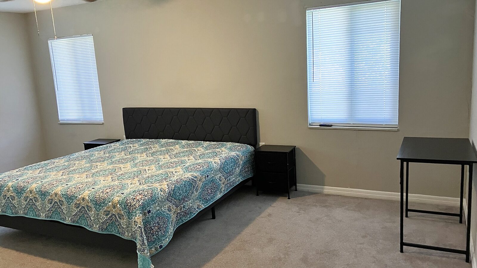 Sarasota bedroom with a blue patterned bedspread, two windows and a writing desk