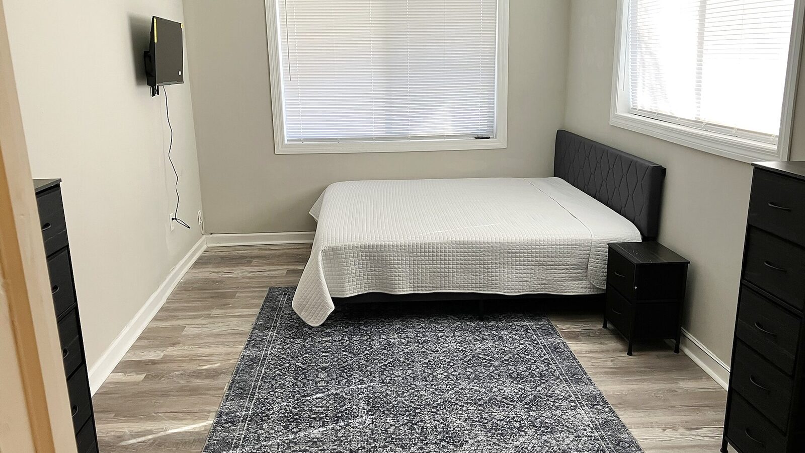 Sarasota bedroom with a white bedspread, black headboard and nightstand beneath bright windows