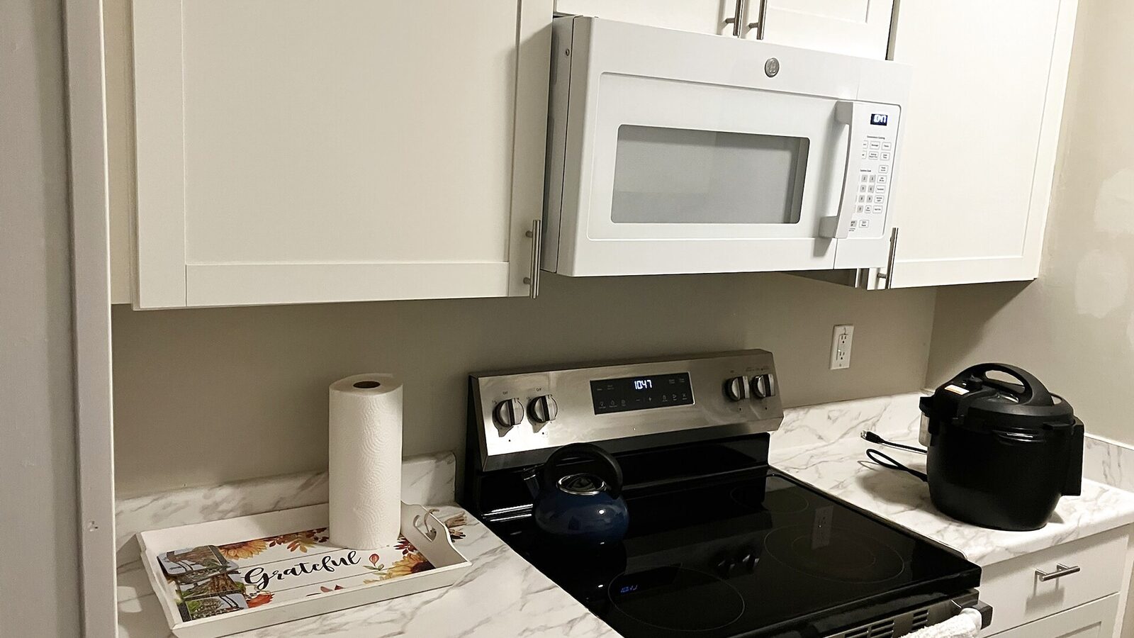 Sarasota house kitchen with white cabinets, a black stove and an over-range microwave